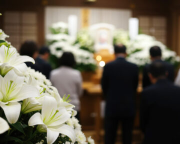 葬儀会場に来た弔問客と白いユリの花のイメージ